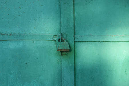 one big old iron green lock hanging on a metal doorの写真素材