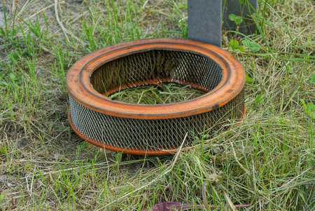 garbage from one old round car filter in the green grass on the street