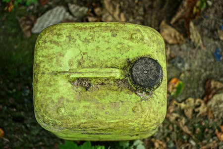 garbage from an old yellow dirty plastic canister on the ground outsideの写真素材