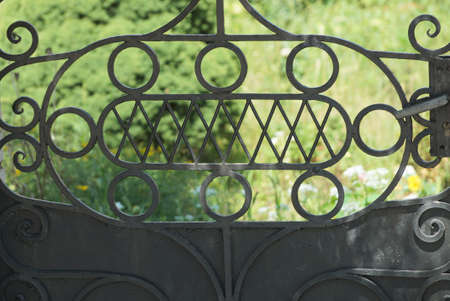 metal texture of black forged pattern of iron rods in the wall of the door on the street on a green backgroundの写真素材