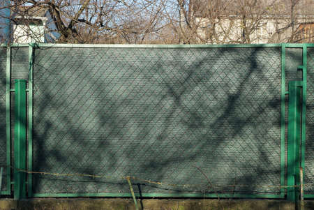 fence wall made of metal green mesh and gray fabric on the street