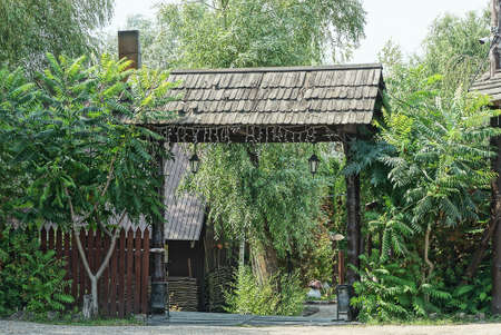 big open wood brown gate and a picket fence in green vegetation outsideの写真素材