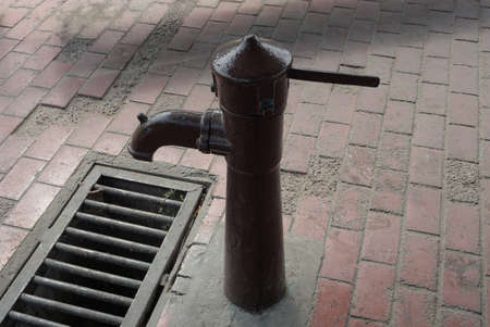 one old brown iron pump in the pump room for pumping water on the sidewalk by the metal grate
