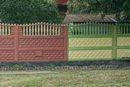colored yellow brown concrete fence wall on rural street in green grassの写真素材