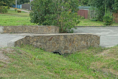 small brown stone bridge in green grass by an asphalt road on the streetの写真素材