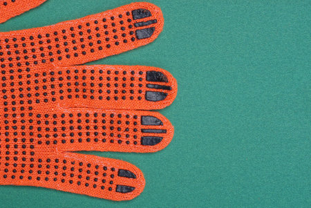 part of one red work glove made of fabric lies on a green tableの写真素材