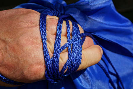 blue rope from a backpack wound on a hand
