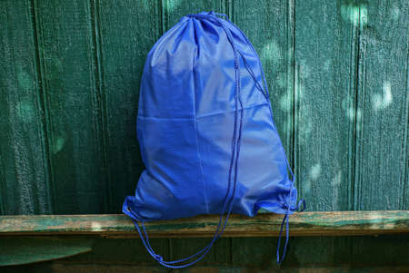 one full blue bag of a backpack made of fabric stands on a bench against a green wall on the streetの写真素材