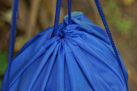 ropes pull together a blue backpack a bag made of synthetic fabric on the street against a gray backgroundの写真素材