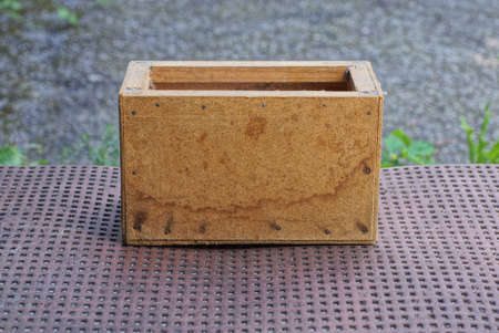 one brown wooden dirty open plywood box stands on a table in the streetの写真素材