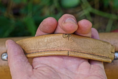hand holds a brown leather handle on an old briefcaseの写真素材