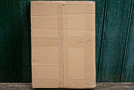 one brown cardboard paper box stands on a gray table against a green wallの写真素材