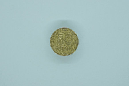 one yellow Ukrainian fifty kopeck coin lies on a white tableの写真素材