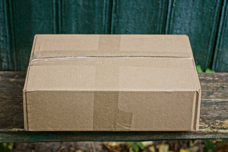 one brown cardboard paper box lies on a gray table against a green wall