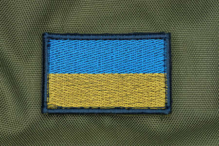 one rectangular blue yellow patch of the Ukrainian flag on the green fabric of the backpackの写真素材