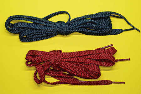 two skeins of red and blue laces lie on a yellow table