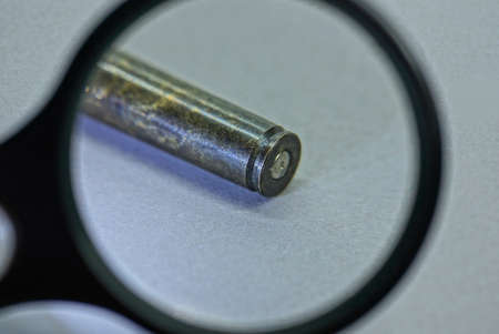 black magnifier magnifies one brown brass sleeve on a gray table