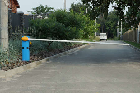white long metal barrier with signal lamp over gray asphalt road in the street