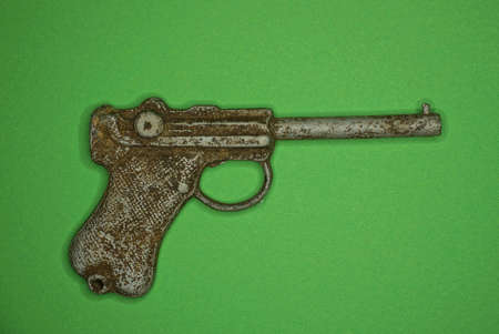 one old gray dirty metal toy gun lies on a green tableの写真素材