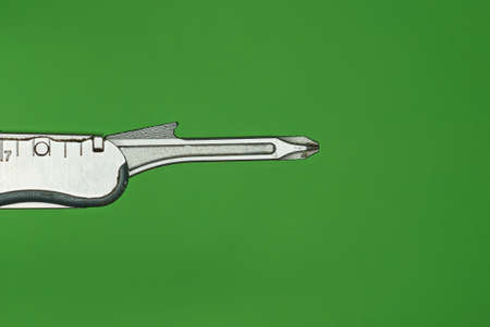 one gray metal screwdriver on the handle of the multitool on a green backgroundの写真素材