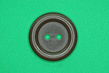 one large round plastic brown button lies on a green tableの写真素材