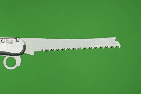 one small gray metal saw on the handle of a multitool on a green backgroundの写真素材