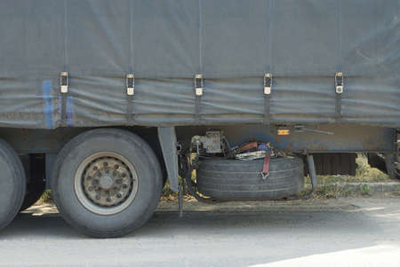 black wheels on a gray large canvas truck trailer on the street on the asphalt road
