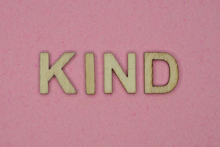 text the word kind from gray wooden small letters on an pink tableの写真素材