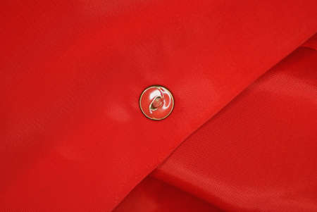 piece of clothing made of red fabric and one small plastic button