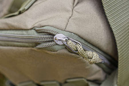 one gray metal zip with drawstring on the green fabric of the backpack