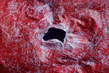 red white plastic texture from a piece of crumpled cellophane with a big black hole