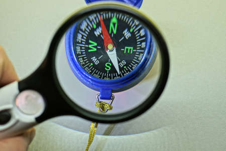 black magnifier in hand magnifies blue compass on gray tableの写真素材