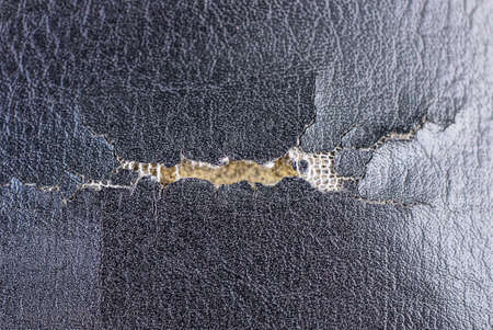 white torn hole with cracks in a piece of black leatherの写真素材
