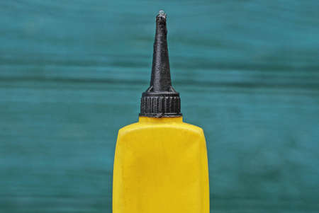 one closed black yellow plastic tube with engine oil on a green backgroundの写真素材
