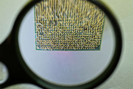 black magnifying glass enlarges old square cpu on gray tableの写真素材