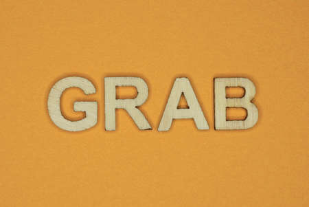gray word grab made of wooden letters on brown backgroundの写真素材