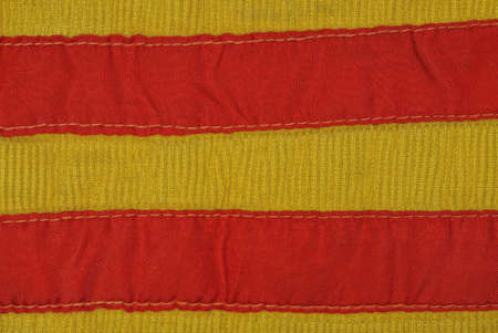 yellow red striped fabric texture from an old piece of clothing with seams