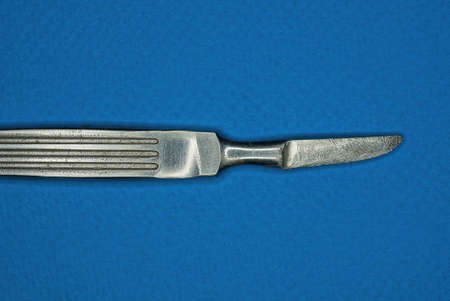 one old gray medical surgical scalpel made of steel lies on a blue tableの写真素材