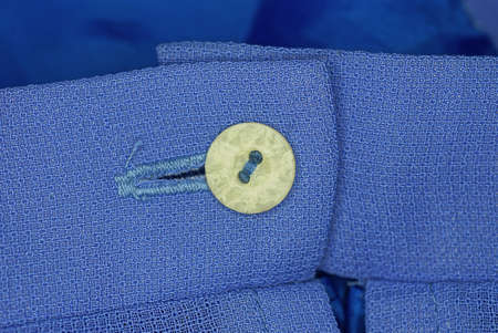 one gray plastic button on the blue fabric of the jacket sleeve