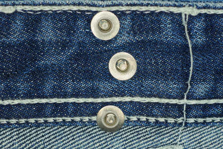 three gray metal rivets on blue cotton fabric