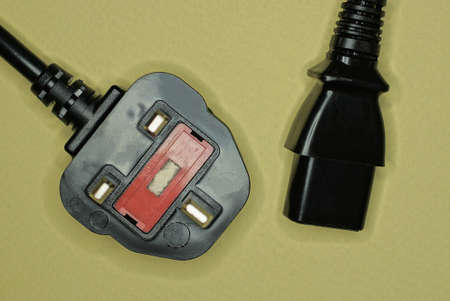 two electrical plugs with a black wire lies on a brown tableの写真素材