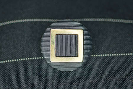 one black large plastic button with a pattern on the striped fabric of the garment