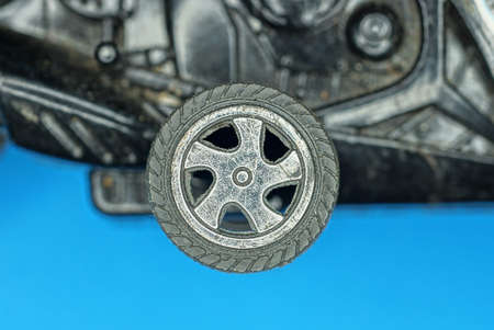 one old plastic small gray black wheel on an old toy on a blue background