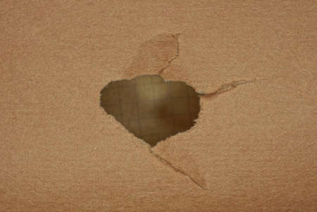 one big gray hole in a piece of brown paper cardboardの写真素材