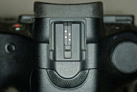 part of a black plastic camera with a speaker and a metal mount for a flash