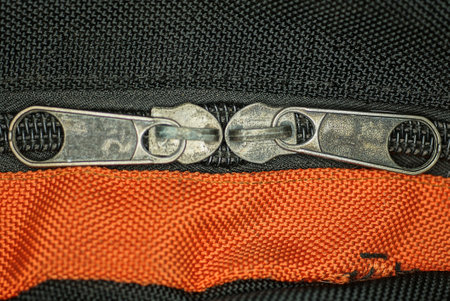 two gray metal zip on a bag made of black and red fabric
