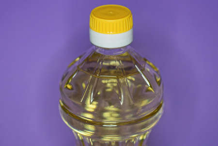 one closed plastic bottle full of sunflower oil on lilac background