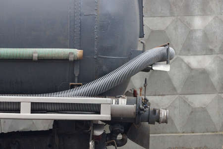 part of a truck made of a gray iron barrel and a plastic hose for sewer cleaning stands on the...