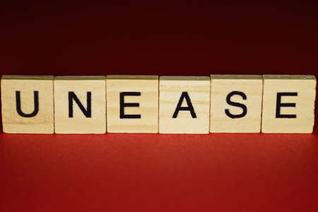 text the word unease from gray wooden small letters on an red table