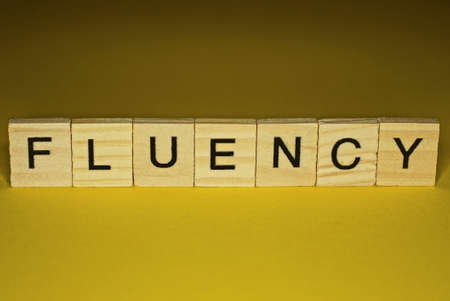 word fluency made from wooden letters lies on a yellow table